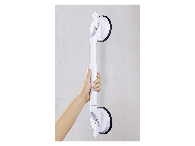 Een hand houdt een wit zuignap-handvat vast dat aan een muur is bevestigd.