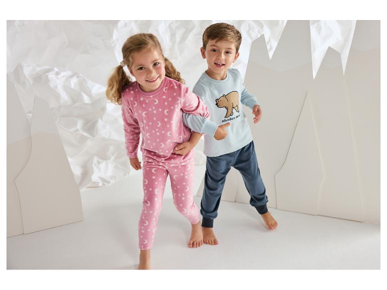 Lachende kinderen in comfortabele pyjama's met sterren- en berenpatronen.