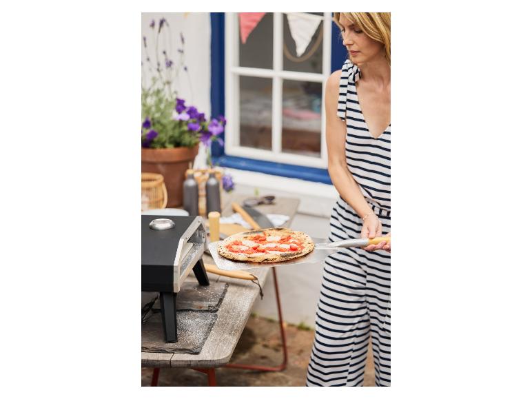 Pizza uit een pizzaoven met pizzaschep.