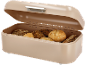 Beige broodtrommel met open deksel, gevuld met diverse soorten brood en broodjes.