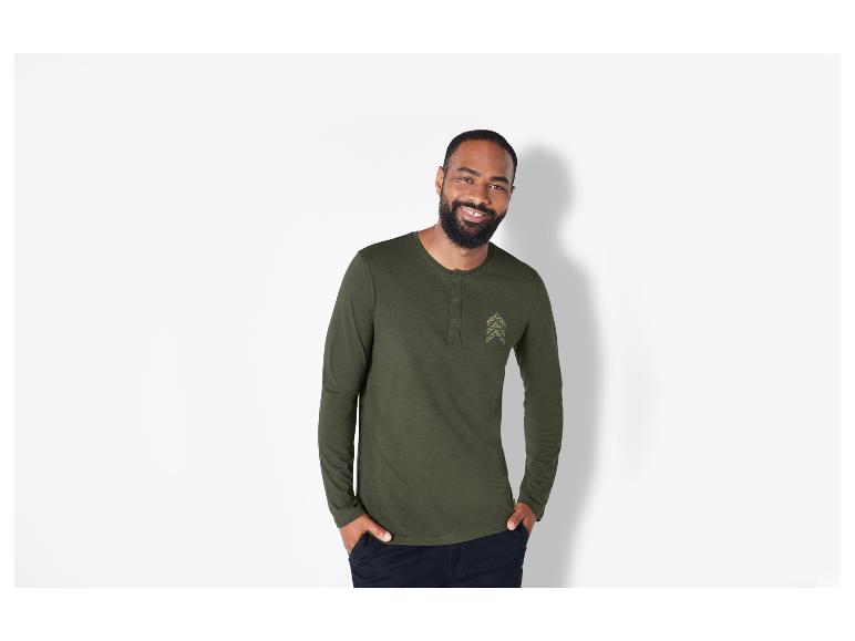 Man draagt een groene lange mouw Henley met een klein logo.