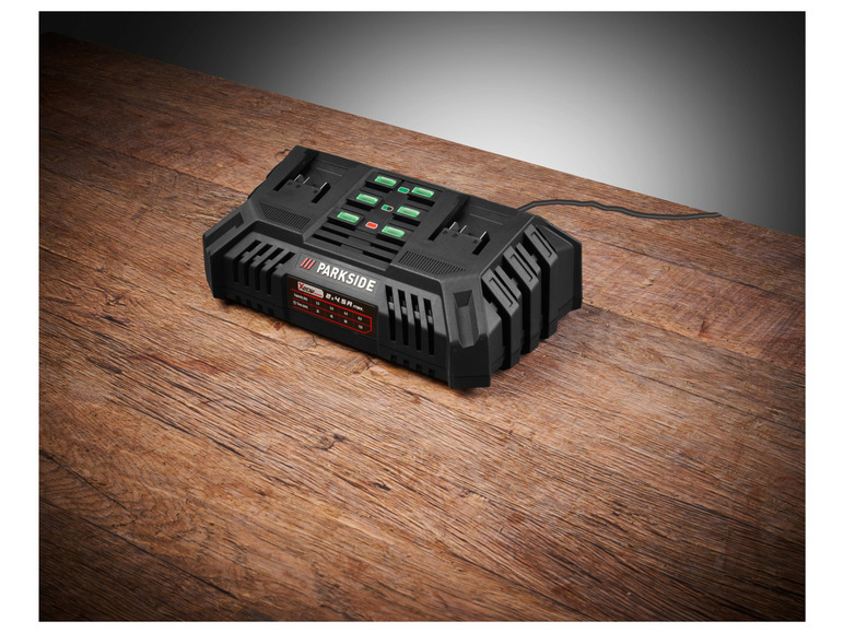 Een zwarte Parkside accu-lader met een snoer op een houten oppervlak.