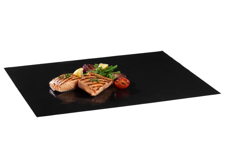 Gegrilde zalm met groenten op een zwarte bakmat.