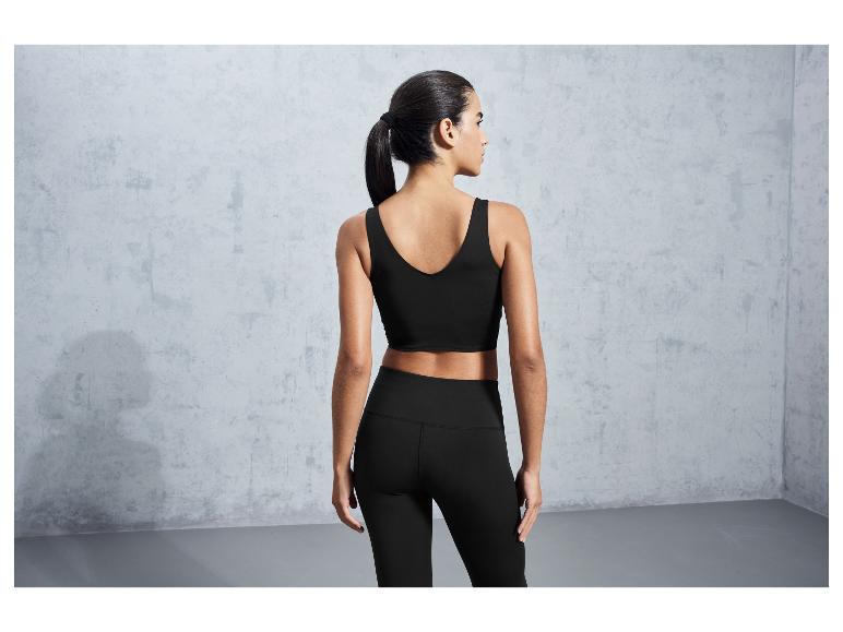 Een vrouw draagt een zwarte sportbeha en leggings.