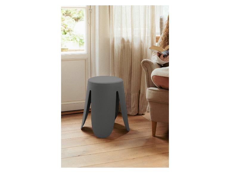 Een lage grijze kruk met vier poten op een houten vloer.