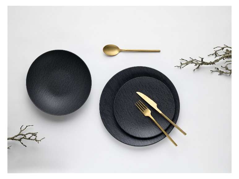 Zwarte borden, gouden bestek en decoratieve takken.