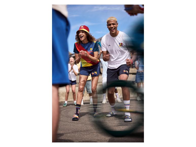 Mensen in sportkleding en slippers met sokken, juichend buiten.