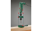 Groene boormachine in een boorstandaard, klaar om in een houten plank te boren.