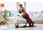 Vrouw traint met kettlebell op een rugtrainer in een lichte kamer.