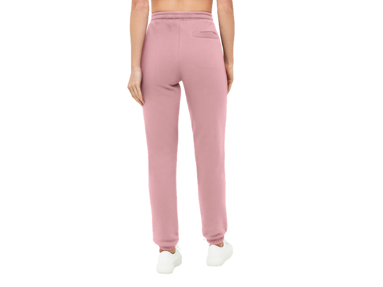 Roze joggingbroek voor dames met elastische tailleband en achterzak, gecombineerd met witte sneakers.