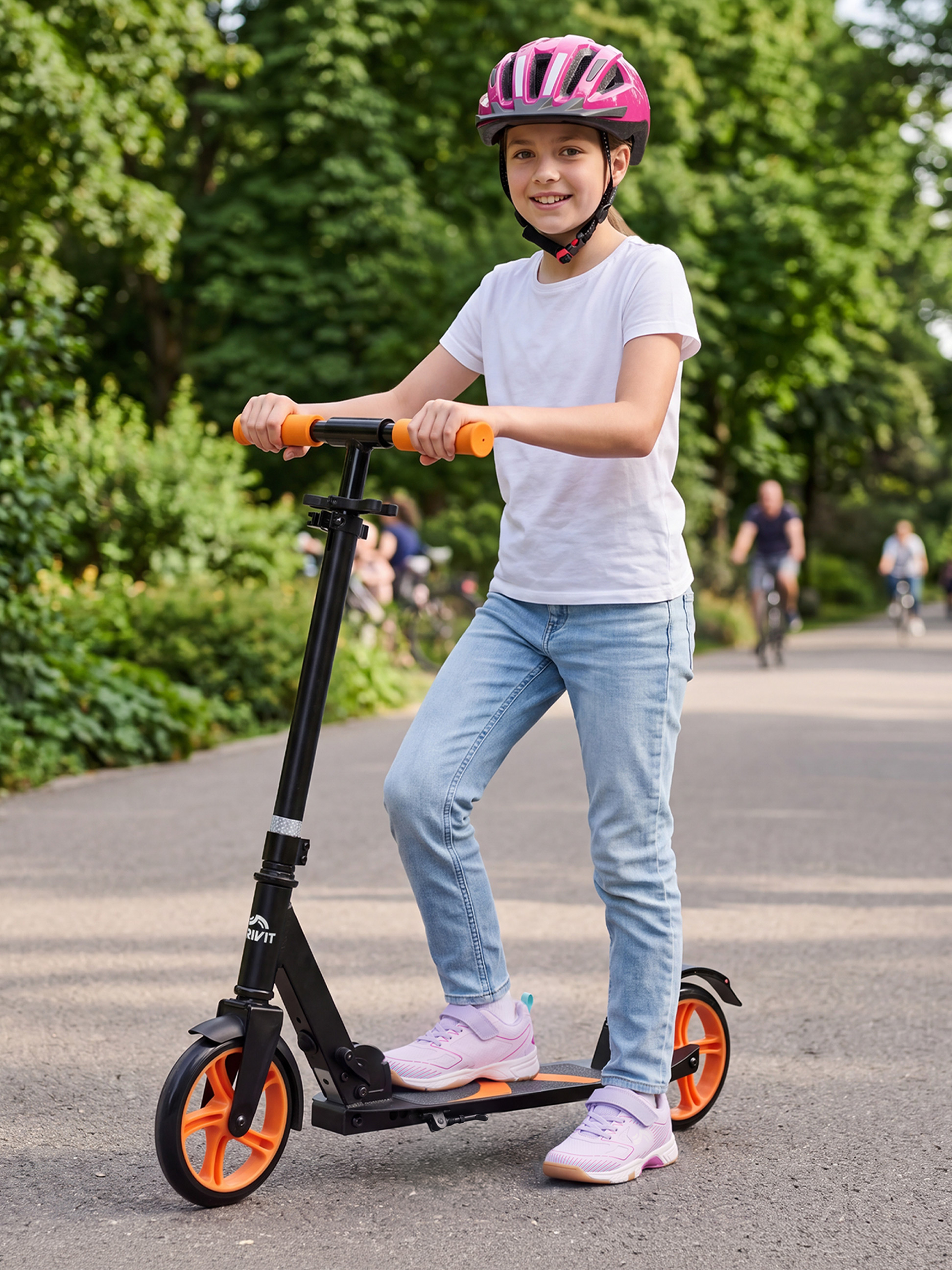 Meisje met roze helm en zwarte step met oranje wielen in een park.