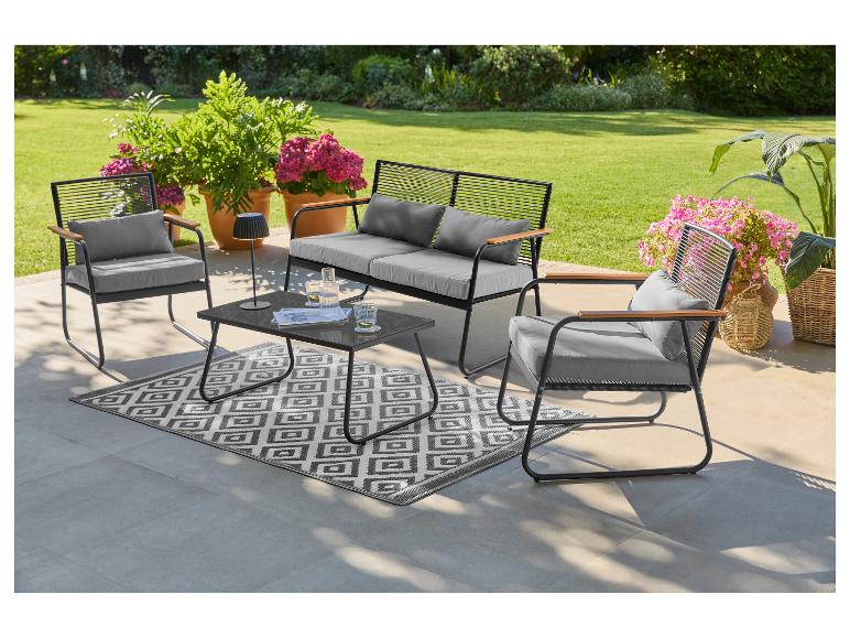 Tuinmeubelset met bank, twee fauteuils, salontafel en vloerkleed op een terras.