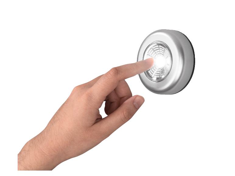 Hand drukt op een zilveren LED-lamp die aan is op een witte achtergrond.