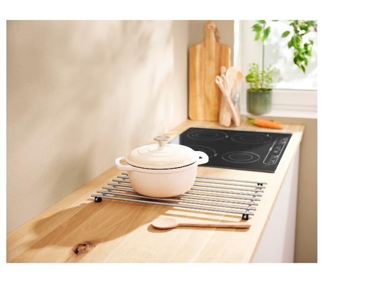 Een stevige keramische pan op een houten tafel met een metalen onderstel.