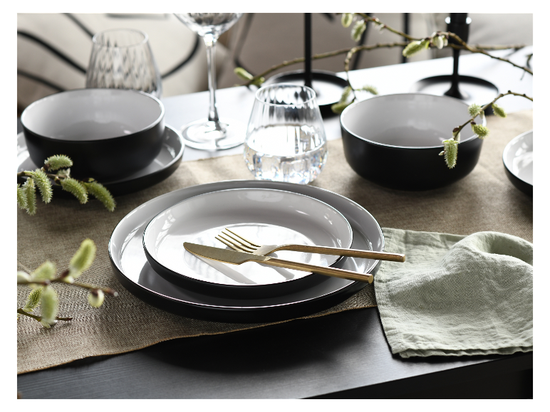 Zwart-wit servies, gouden bestek, minimalistische stijl.