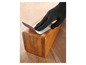 Een hand in een zwarte handschoen schuurdt een houten blok met schuurpapier.