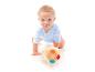 Lachende baby in blauwe romper speelt met een kleurrijke bal op een witte achtergrond.