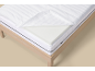 Wit matras met afneembare hoes en traagschuimlaag op een houten bedframe.