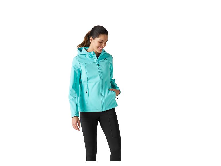 Vrouw in een turquoise capuchonjas en zwarte broek.