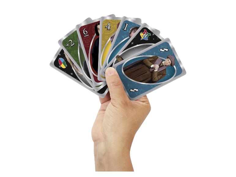 Hand met een waaier van Harry Potter-thema speelkaarten, met personages en huissymbolen.