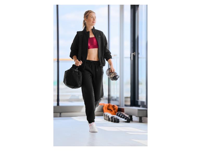 Vrouw in CRIVIT sportjas met sporttas en waterfles.