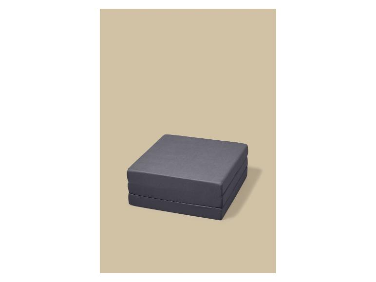 Grijze opvouwbare matras op een beige achtergrond.