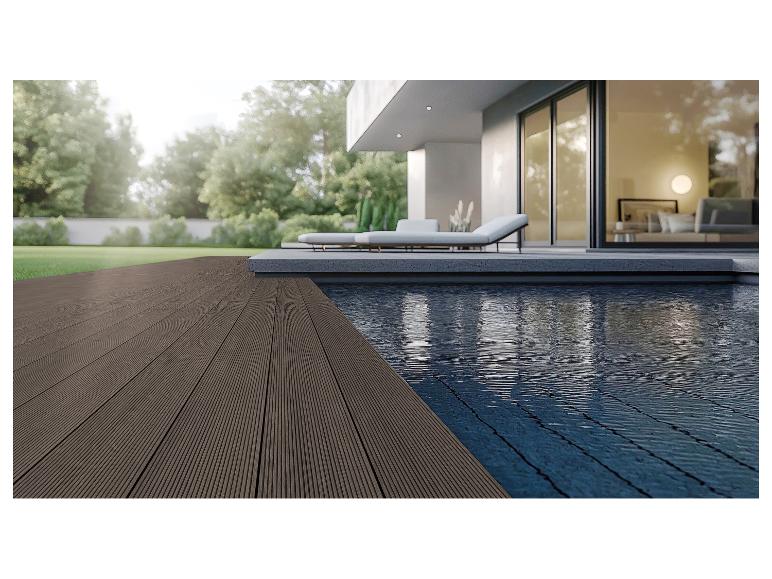 Modern terras met donkere composiet vlonderplanken en zwembad, omgeven door groen.