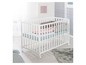 Een wit babybedje met matras, dekbed en kussen.