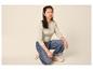 Vrouw in beige shirt met lange mouwen en wijde jeans, gehurkt.