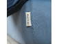 Close-up van blauw textiel met een wit label met zwarte tekst.