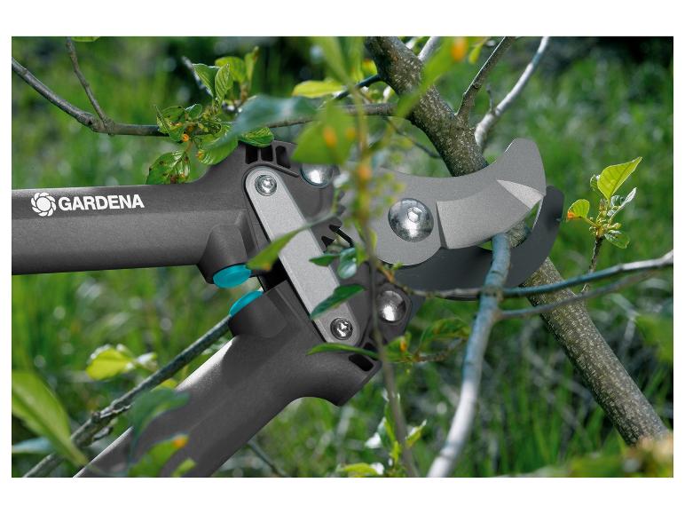 GARDENA snoeischaar snijdt een boomtak met groene bladeren.