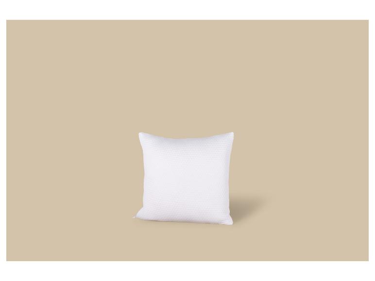 Wit, getextureerd kussen op een beige achtergrond.