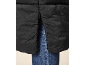 Detail van een zwarte gewatteerde jas met zijrits, gedragen over een blauwe jeans.