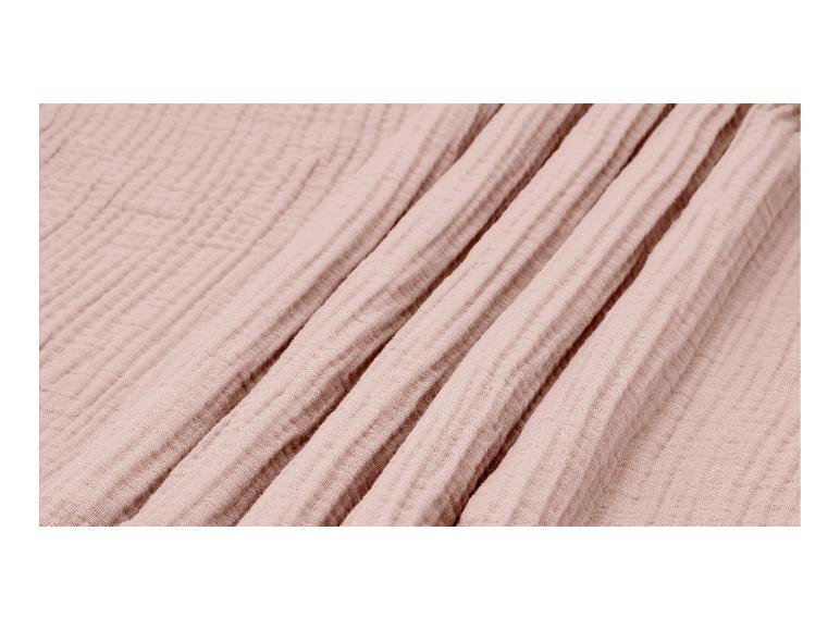 Close-up van een zachte, lichtroze mousseline stof met subtiele kreukels en plooien