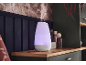 Een gloeiende aromadiffuser die nevel verspreidt op een houten plank in een gezellige kamer.