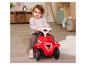 Baby zit op een rode loopauto in een kinderkamer.