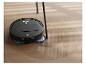 Zwarte robotstofzuiger reinigt een houten vloer met visgraatpatroon.
