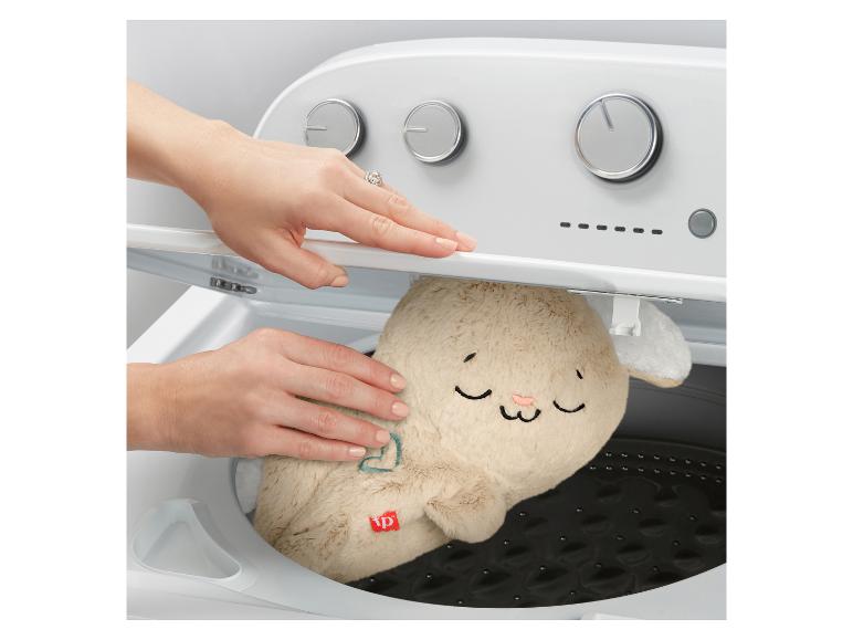 Een persoon stopt een pluchen konijn in een wasmachine.