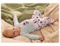 Baby ligt op de rug, draagt een lichtblauwe romper en gestippelde broek.