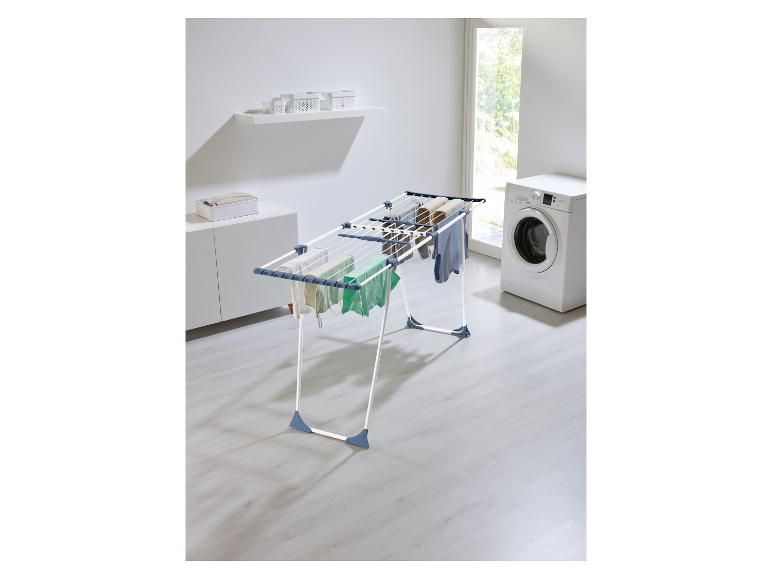 Droogrek met kleding in een wasruimte met wasmachine en kasten.