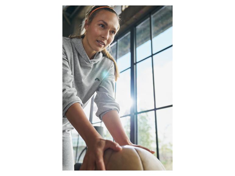 Vrouw in grijze hoodie met oefenbal.