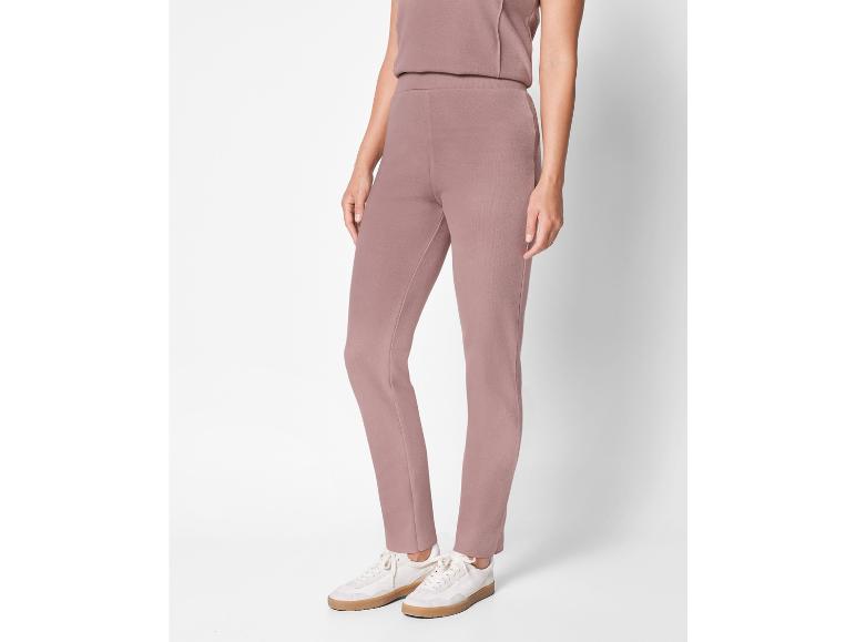 Een vrouw draagt ​​een roze broek en witte sneakers.