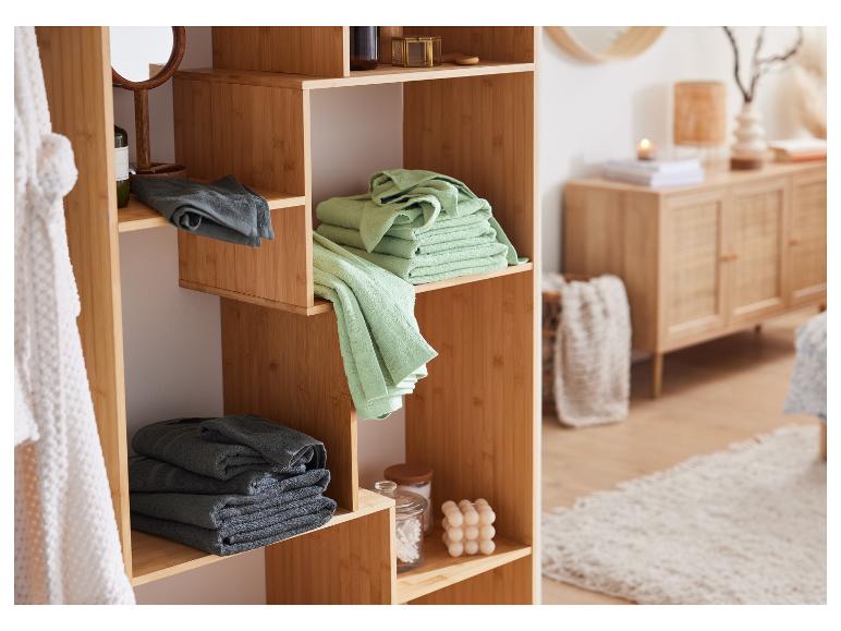 Een houten badkamerrek met handdoeken, een spiegel en badproducten.