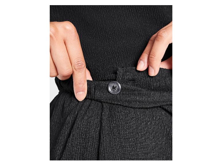 Close-up van een zwarte broek met een knoop.