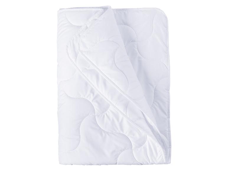 Witte, gewatteerde deken, gevouwen op een witte achtergrond.