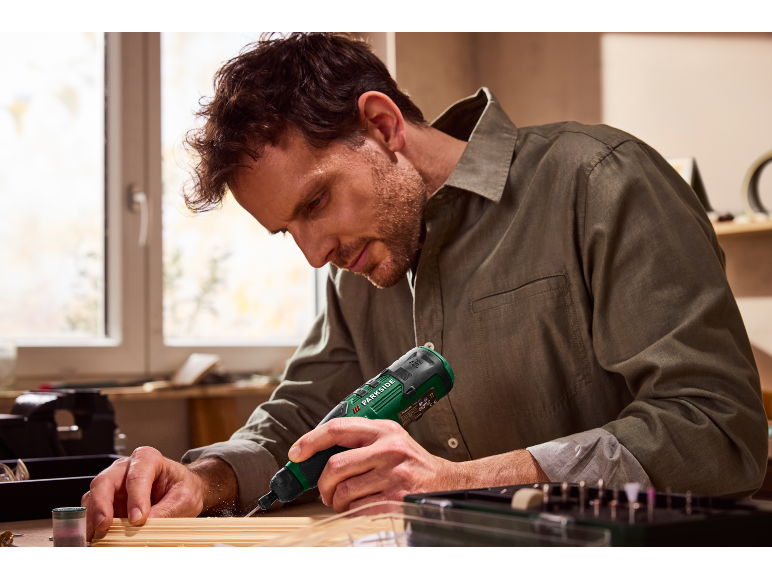 Man gebruikt een Parkside roterende tool om hout te bewerken.