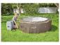 Vrouw installeert opblaasbare jacuzzi op gras in een tuin.
