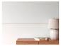 Witte muur met Grieks patroon, houten ladekast, lamp, boek en kaars.