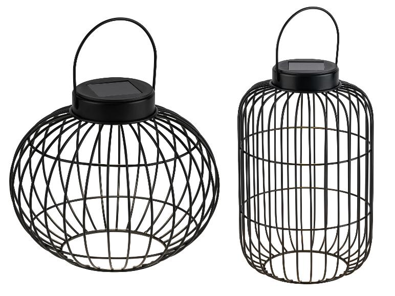 Twee zwarte metalen decoratieve solarlantaarns, één bolvormig en één cilindrisch.
