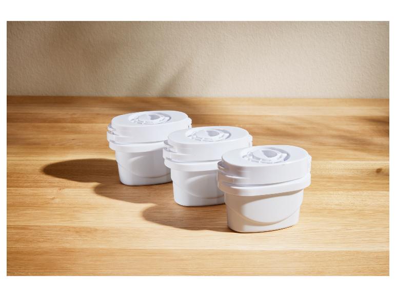 Drie witte waterfilterpatronen op een houten tafel.